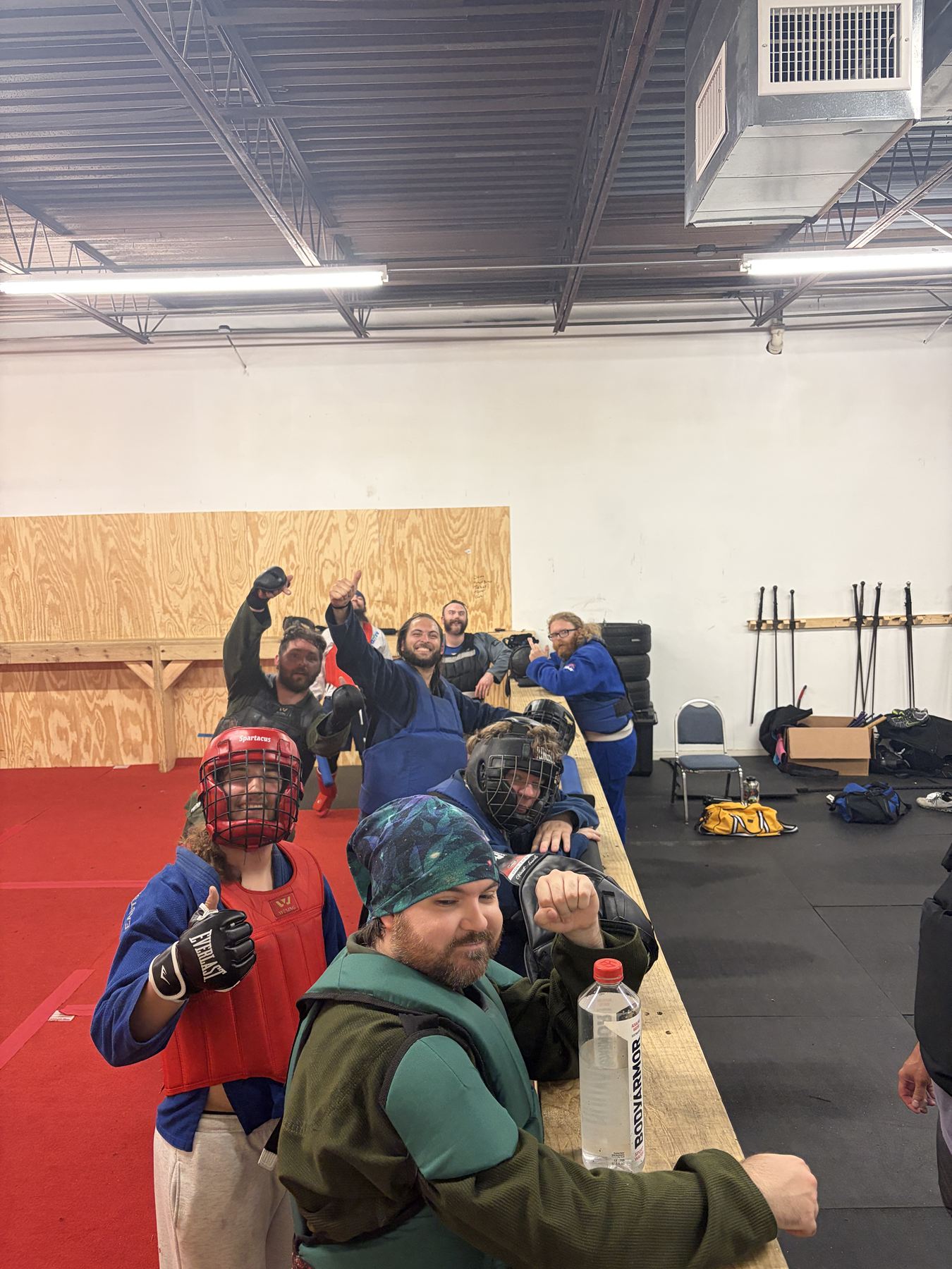 Fighters in padded kit cheering along the bench at practice