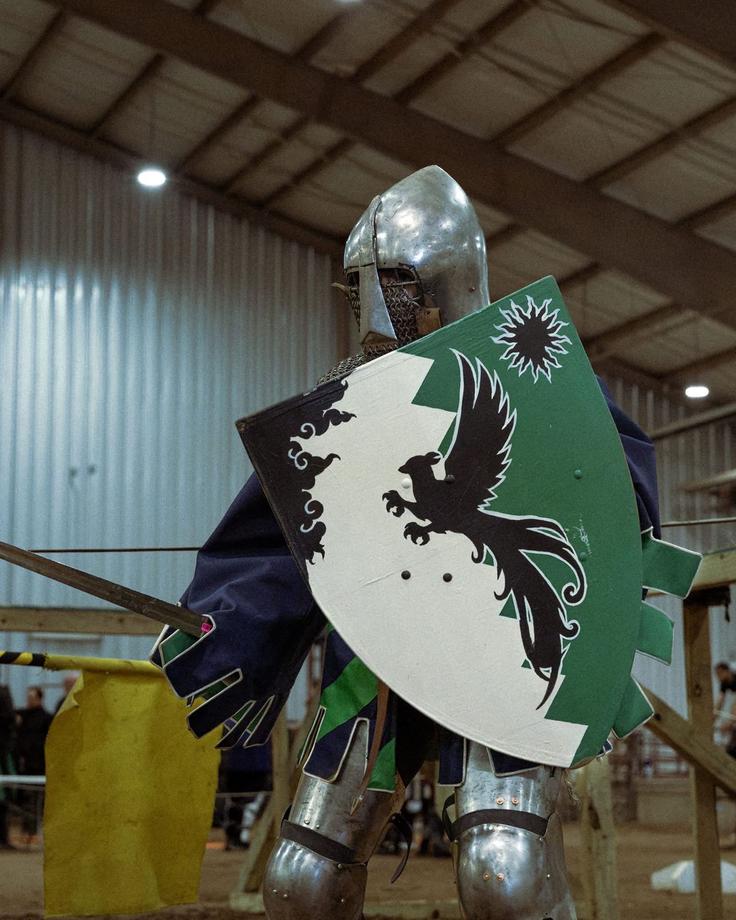 A fighter behind a green and white shield painted with a black raven